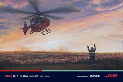 A cropped image of the 2027 STARS Calendar cover, showing STARS Very Important Patient, writer, and artist Shelly Campbell's painting titled Golden Hour, a STARS air ambulance helicopter landing in a field, guided by a lone firefighter at dusk.