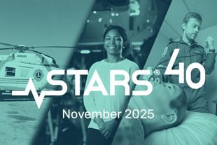 Stars 40 promotional image featuring two people in an aircraft hangar with a helicopter in the background, November 2025 text overlay in teal tone