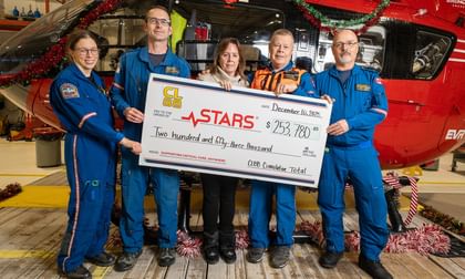 STARS ally Cindy Letourneau poses alongside STARS operations crew members during a cheque presentation at the STARS base in Calgary. The cheque recognizes the total donated amount of $253,780 that Cindy has raised in honour of her son Chris who was flown by STARS in 2013, but passed from his injuries shortly after.