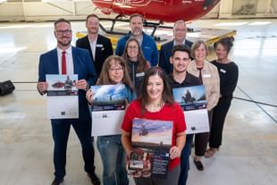 STARS Very Important Patients pose with their calendar spreads, alongside STARS staff and representatives from Bunge, the calendar sponsor, during the 2027 Calendar launch event at the Calgary hangar. A STARS air ambulance helicopter sits in the background.