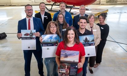 STARS Very Important Patients pose with their calendar spreads, alongside STARS staff and representatives from Bunge, the calendar sponsor, during the 2027 Calendar launch event at the Calgary hangar. A STARS air ambulance helicopter sits in the background.