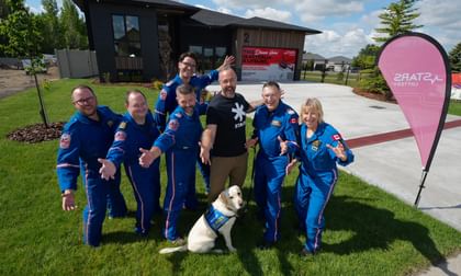 STARS operations staff, accompanied by PADS service dog Orion, gather around STARS very important patient Mike Herbison outside the STARS LOTTERY Saskatchewan dream home in Regina, Sask.