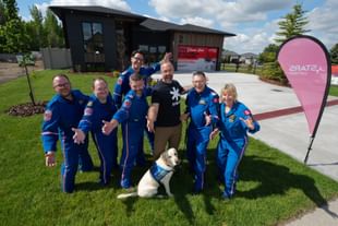 STARS operations staff, accompanied by PADS service dog Orion, gather around STARS very important patient Mike Herbison outside the STARS LOTTERY Saskatchewan dream home in Regina, Sask.