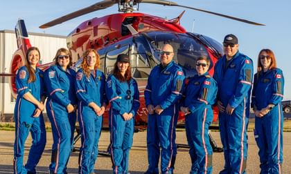 STARS operations staff and participants of the 2026 Rescue in the North event dressed in blue flight suits, standing in front of a red STARS air ambulance helicopter.