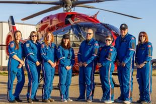 STARS operations staff and participants of the 2026 Rescue in the North event dressed in blue flight suits, standing in front of a red STARS air ambulance helicopter.