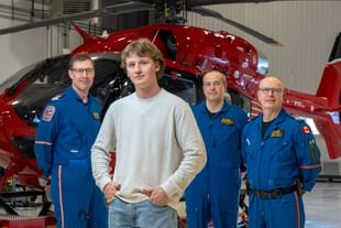 STARS Very Important Patient Thomas Wright stands in front of a STARS air ambulance helicopter alongside the STARS crew that worked on his mission.