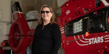 STARS Very Important Patient Carrie Derin stands in front of a STARS air ambulance helicopter during a visit to her nearest STARS base.