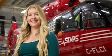 STARS Very Important Patient Dominque Wiebe stands in front of a STARS air ambulance helicopter during a visit to her closest STARS base.