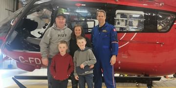 STARS Very Important Patient Doug MacTavish poses with his family and a member of STARS' operations staff in front of a STARS air ambulance helicopter during a visit to his closest STARS base.