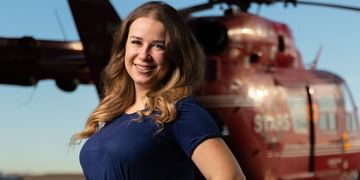 STARS Very Important Patient Justeen Kolody poses in front of a STARS air ambulance helicopter during a visit to her nearest STARS base.