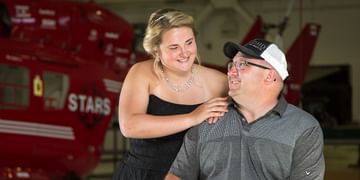 STARS Very Important Patient Jason Lunn sits in his wheelchair, talking to his daughter while in front of a STARS BK117 air ambulance helicopter in this older photo.