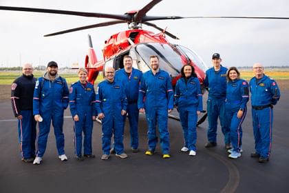 STARS Rescue on the Prairie 2024 participants pose together in front of a STARS air ambulance helicopter, flanked by STARS operations staff. The photo was taken the morning of the event on the apron just outside of the STARS hangar.