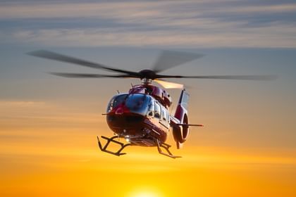 A STARS air ambulance H145 helicopter hovers above the ground at sunrise, with the sun barely peeking from the bottom of the frame.