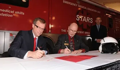 Then Saskatchewan Premier Brad Wall and STARS founder and then president Dr. Greg Powell sign documents contracting STARS to provide service to the people of Saskatchewan. STARS ambassador and supported Rod Gantefor looks on in the background.
