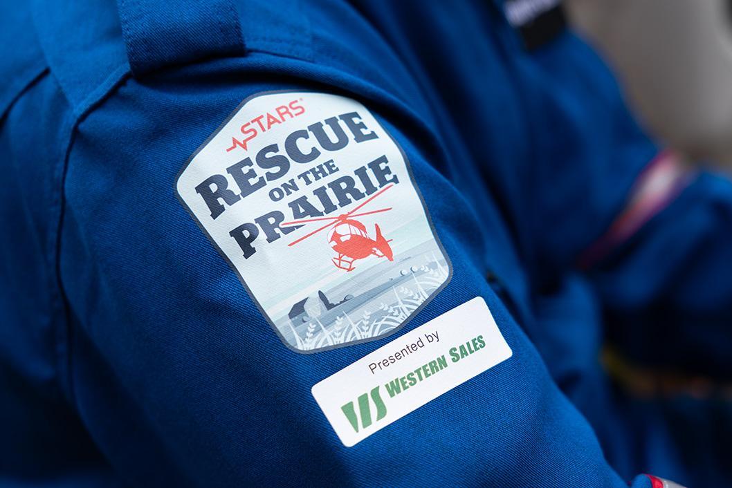 A participant patch on a blue flight suit shoulder showing the 2025 STARS Rescue on the Prairie patch and a second patch with the sponsor Western Sales logo.