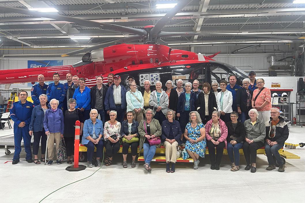 Volunteers and supporters of the Morden Community Thrift Shop pose with STARS operations staff in front of a STARS H145 air ambulance during the organization's logo unveiling on the helicopter.