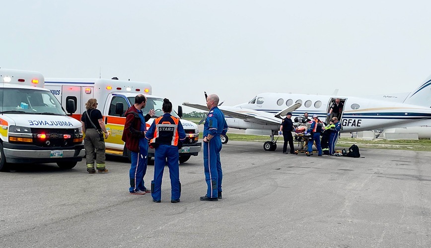 A patient is transferred from ground ambulance to a fixed-wing critical care flight at the Brandon Airport.