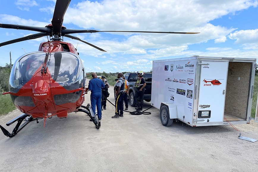 STARS pilot Jason Johnson fuels STAR-7 from a mobile fuel cache alongside members of the Winnipegosis Fire Department and local RCMP.