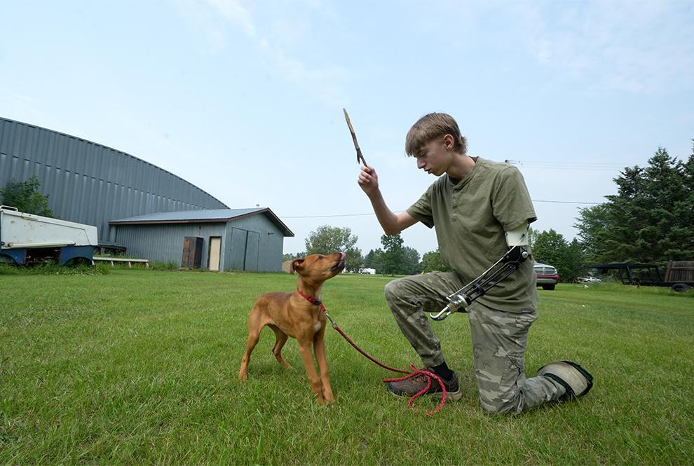 STARS Very Important Patient holds a stick while playing with a puppy at the scene of his accident. His prosthetic arm faces the camera.